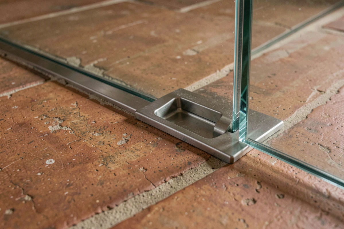 Détail de la poignée encastrée d'une trappe en verre feuilleté affleurant un carrelage en terre cuite dans une maison ancienne